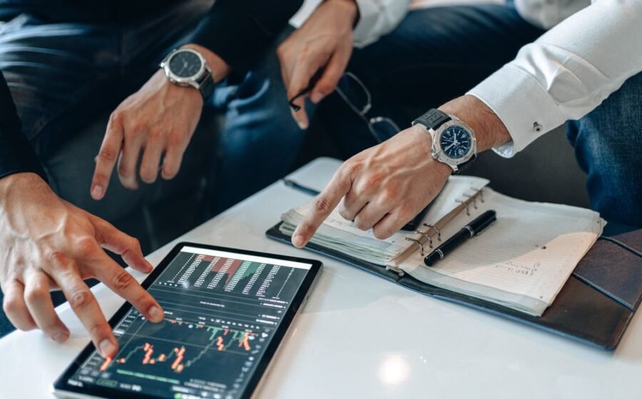 wealthtech funding drops - Two businessmen discussing financial data on a tablet during a meeting.
