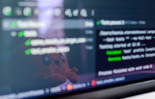 kraken sofi stablecoin - Close-up of a laptop screen displaying programming code with a cute plush toy reflecting.