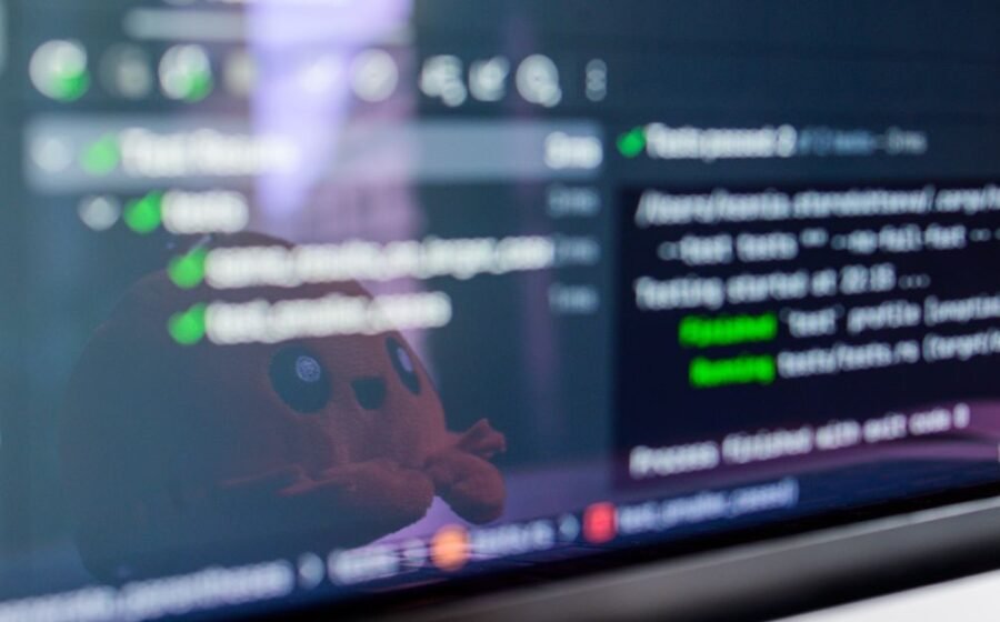 kraken sofi stablecoin - Close-up of a laptop screen displaying programming code with a cute plush toy reflecting.