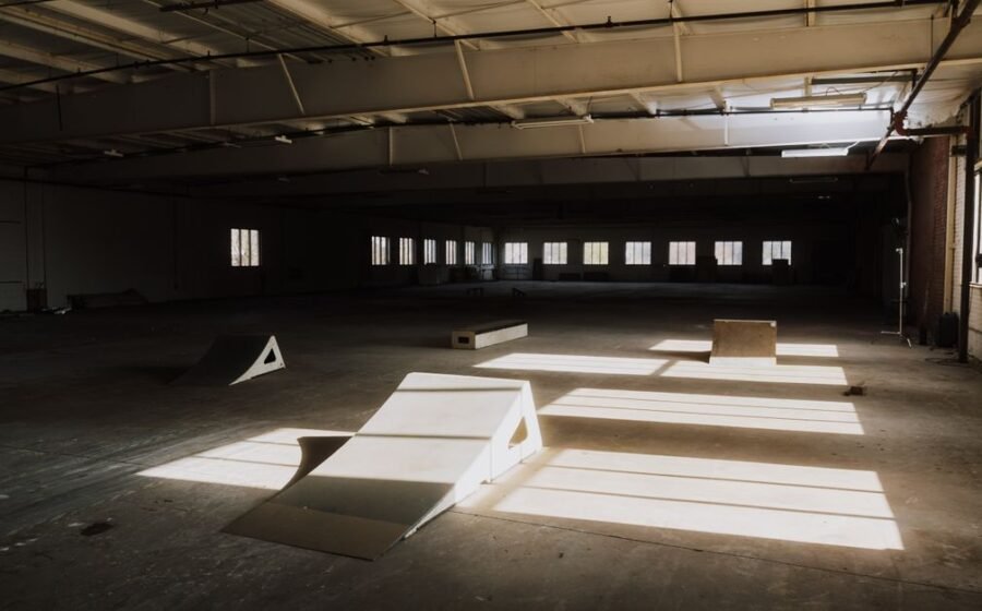 ramp valuation - Sunlight casting shadows over ramps in an empty indoor skate park.